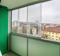 A glazed balcony with a view of the buildings on SNP Avenue in Banská Bystrica.