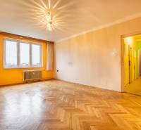 A spacious room with a wood-patterned floor and an orange wall in a 2-room apartment.