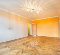Living room with wood-patterned flooring and an orange wall in a two-room apartment.