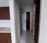 A kitchen with dark cabinets and white tiles in a studio apartment.