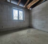 Interior of a family house with raw walls, a window, and a concrete floor.