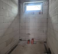 Unplastered walls, small window, and PVC pipes in a family house.