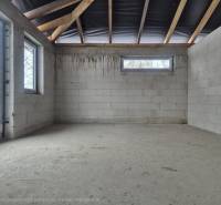 Unfinished interior of a family house with a concrete floor and frameless windows.