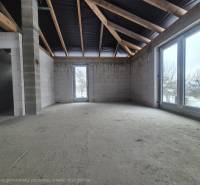 Unfinished interior of a family house with a concrete floor and large windows.