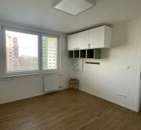 Interior of a one-room apartment with wood-patterned flooring and white walls, bright space.