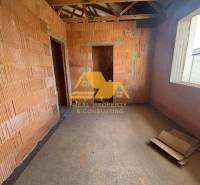 The interior of an unfinished family house with exposed bricks and construction materials.