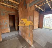 An unfinished family house with a view of walls without plaster and a wooden roof structure.