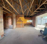 Interior of a family house under construction with exposed brick walls and a wooden ceiling.