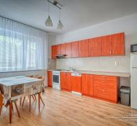 A kitchen in a family house with an orange kitchen unit, a dining table, and a bright interior.