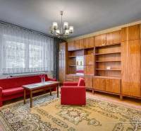 Living room in a family house with red sofas, a chandelier, and a wooden wall unit.