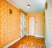 A room in a family house with orange wallpaper and parquet flooring.