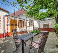 A garden of a family house in Trnava with a wooden table and chairs in the yard.