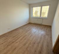 A room in a 2-room apartment with a wooden decor floor and a large window.