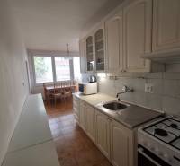 A kitchen in a 3-room apartment with a gas stove and a dining table.