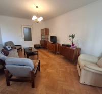Living room of a 3-room apartment with a wooden decor floor, retro furniture, and comfortable armchairs.