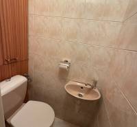 A bathroom with beige tiles, a toilet, and a small sink in a 3-room apartment.