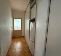 A narrow hallway with storage space and a tiled floor in a 3-room apartment.