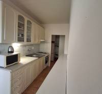 A kitchen with white cabinets and appliances in a 3-room apartment, floor with ceramic tiles.