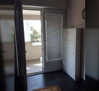 Balcony entrance in a family house with tiled floor and white furniture.