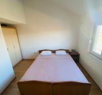 Bedroom in a family house with a bed, nightstand, and floor with wooden decor.