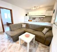 Interior of a family house with a sofa, white table, and kitchenette.