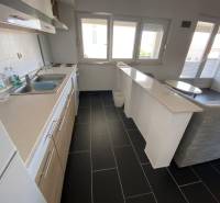 A kitchen in a family house with a dark wood-patterned floor and a bar counter.