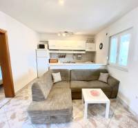 Living room in a family house with a sofa and a kitchenette, tiled floor.