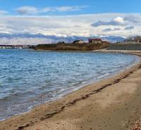 The coast in Nin with a sandy beach, view of houses and snowy mountains.