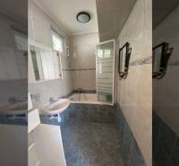A bathroom in a family house with ceramic tiles and a shower enclosure.