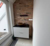 A small sink corner in a 4-room apartment with a brick wall and a wooden decor floor.
