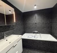 Elegant bathroom with dark tiles and a bathtub in a 4-room apartment.