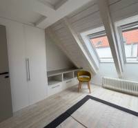 Attic room with wood-decor flooring, built-in wardrobe, and yellow chair.