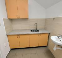 A kitchenette in commercial premises with yellow cabinets and a sink.