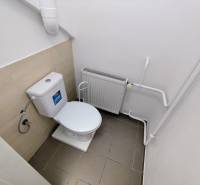A restroom in commercial premises with a radiator and white walls.