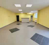 Interior of commercial spaces with tiled flooring and a reception area, illuminated by ceiling lights.