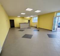 Commercial space with tiles and reception, yellow walls, large windows, entrance doors.