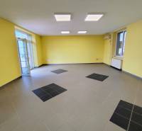 Commercial premises with yellow walls and gray tiles, light from windows, air conditioning.