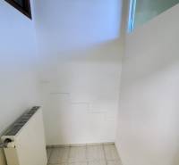 Commercial space with a radiator and white walls, floor with white tiles.