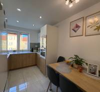 A kitchen in a 2-room apartment, light tiles, a table with decorations, pictures on the wall.