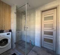 Bathroom in a 2-room apartment with a shower, washing machine, and storage space.