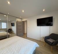 Two-room apartment with TV, wardrobe, and wooden decor flooring.