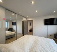 A bedroom in a two-room apartment with a television, a large wardrobe, and a floor with a wooden decor.