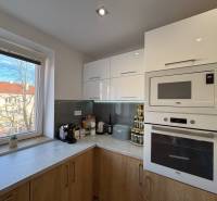 Kitchen in a 2-room apartment with white cabinets and a wooden decor floor.