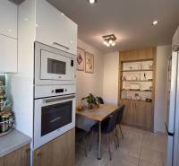 A kitchen in a 2-room apartment with modern appliances, a dining table, and storage cabinets.