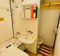 Bathroom with a sink, washing machine, and toilet in a 2-room apartment, simple storage solutions.
