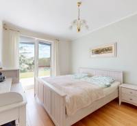 A bedroom in a family house with a wooden decor floor and a view of the garden.