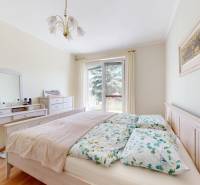 A bedroom in a family house with a bed, a dressing table, and a floor with a wooden decor.