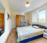 Bedroom in a family house with wood-patterned flooring, a mirror, and a bed.