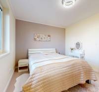 A bright bedroom in a family house with a bed and a table.