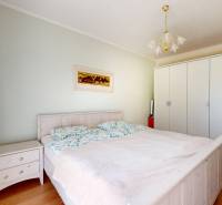 Bright bedroom with a double bed, wardrobes, and a wooden decor floor in a family house.